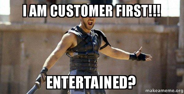 A gladiator in a coliseum with arms outstretched, shouting. The text above reads "I AM CUSTOMER FIRST!!!" and the text below reads "ENTERTAINED?