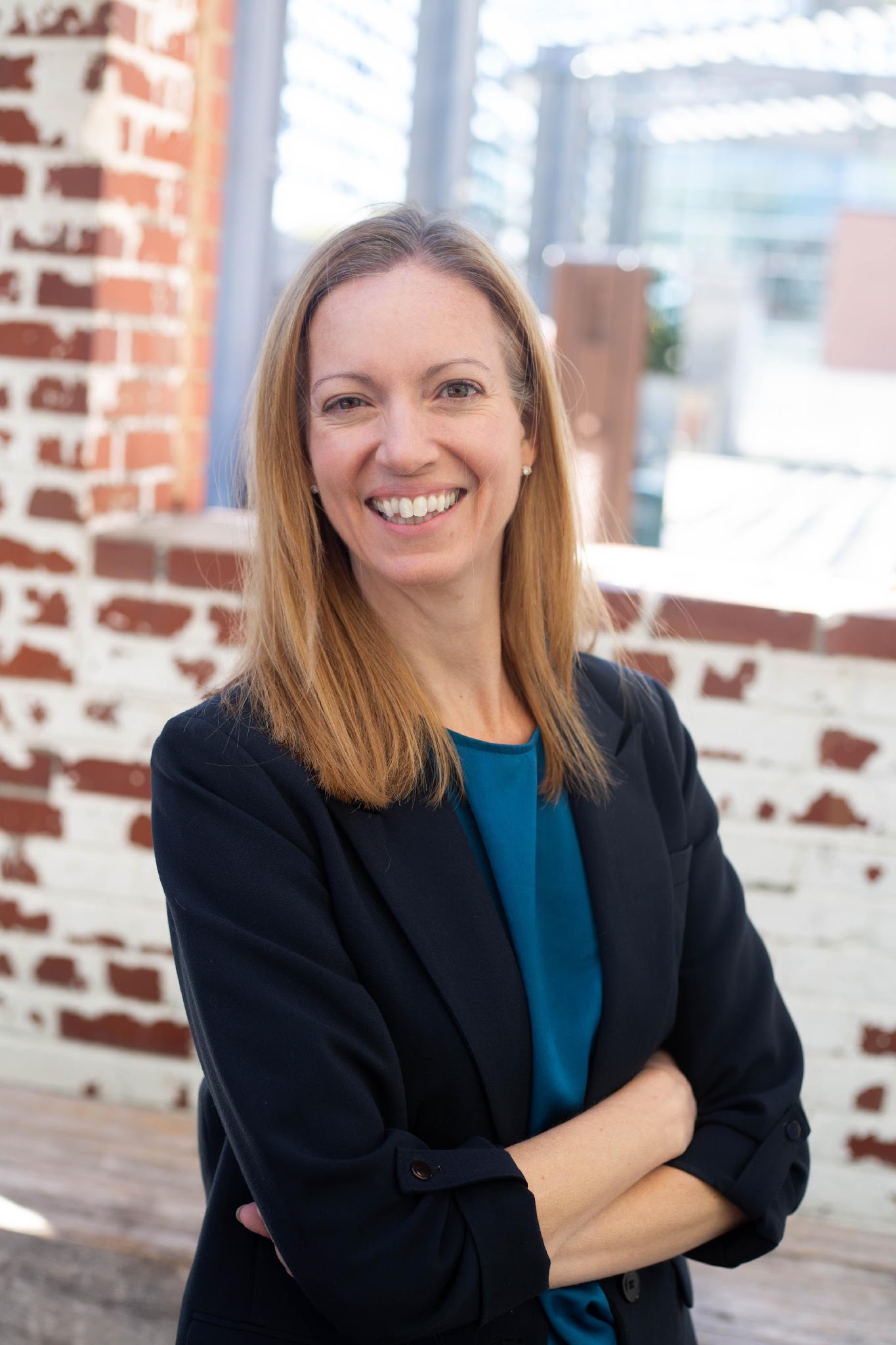 A person smiling with her arms crossed Description automatically generated