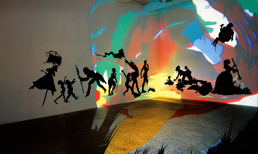 Installation. Paper cut-outs and projections in a white room, colorful lights illuminate black silhouettes of humans. This view of the installation shows the corner of a white-walled room. The life-sized silhouettes of human figures are illuminated by colorful lights in red, yellow, blue, green, and white. There are over a dozen figures, ranging from infant to adult-sized. All of the figures are flat, black, paper cutouts applied to the white walls in animated positions. From left to right, based on the silhouette:
1. A figure, wearing a full skirt, grasps a pole with a sail. 
2. Two toddler-sized figures stride, nude, towards an adult. 
3. A figure faces the two toddlers, bent down to their level, wearing shoes with high heels. 
4. An adult sized figure is facing directly opposite the previous figure. There appears to be a baseball-style hat. 
5. Another adult figure is crouching while reaching upwards. 
6. An adult silhouette is holding a triangular-shaped flag, arms thrown back. 
7. This adult silhouette appears to be missing one leg below the knee, the severed limb on the ground. 
8. This group of figures seems to be a mother and her three children. She is crawling on hands and knees, her exposed breasts drooping. 
9. Finally, the figure on the far right seems to represent a woman in a fancy dress, using a weapon to attack a figure on the ground in front of her. 