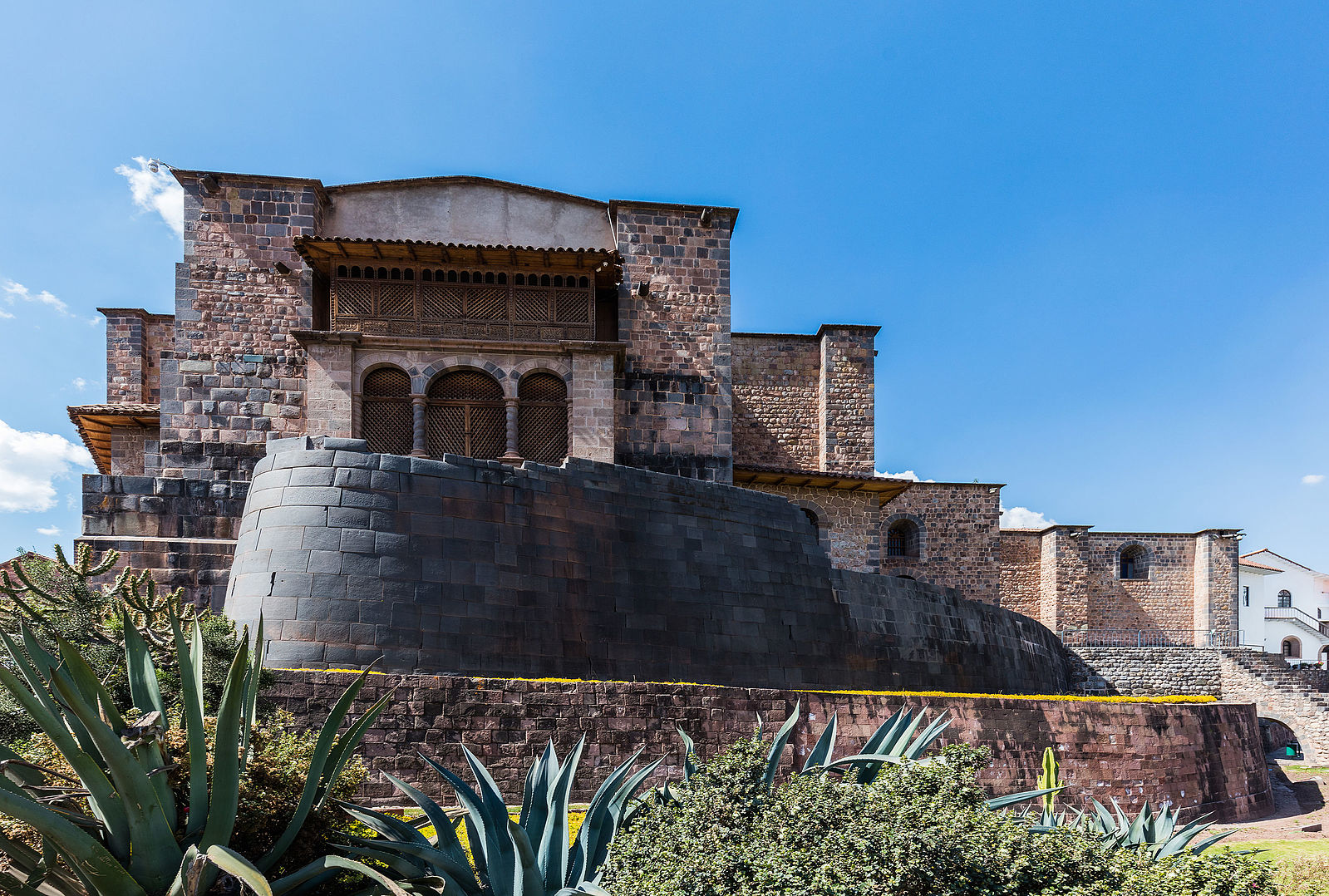 Architecture. Building atop a series of walled terraces, its masonry is irregular-shaped stones forming smooth surfaces.
The walls, built with this irregular and unusual masonry style, taper upward, with the doors and windows in distinctive trapezoid shapes. The overall building is multi-storied, with split levels and one main entrance. This entrance in the front of the main floor consists of three tall archways, the widest arch in the middle. A smooth, rounded wall encloses most of the fist level of the facade.

